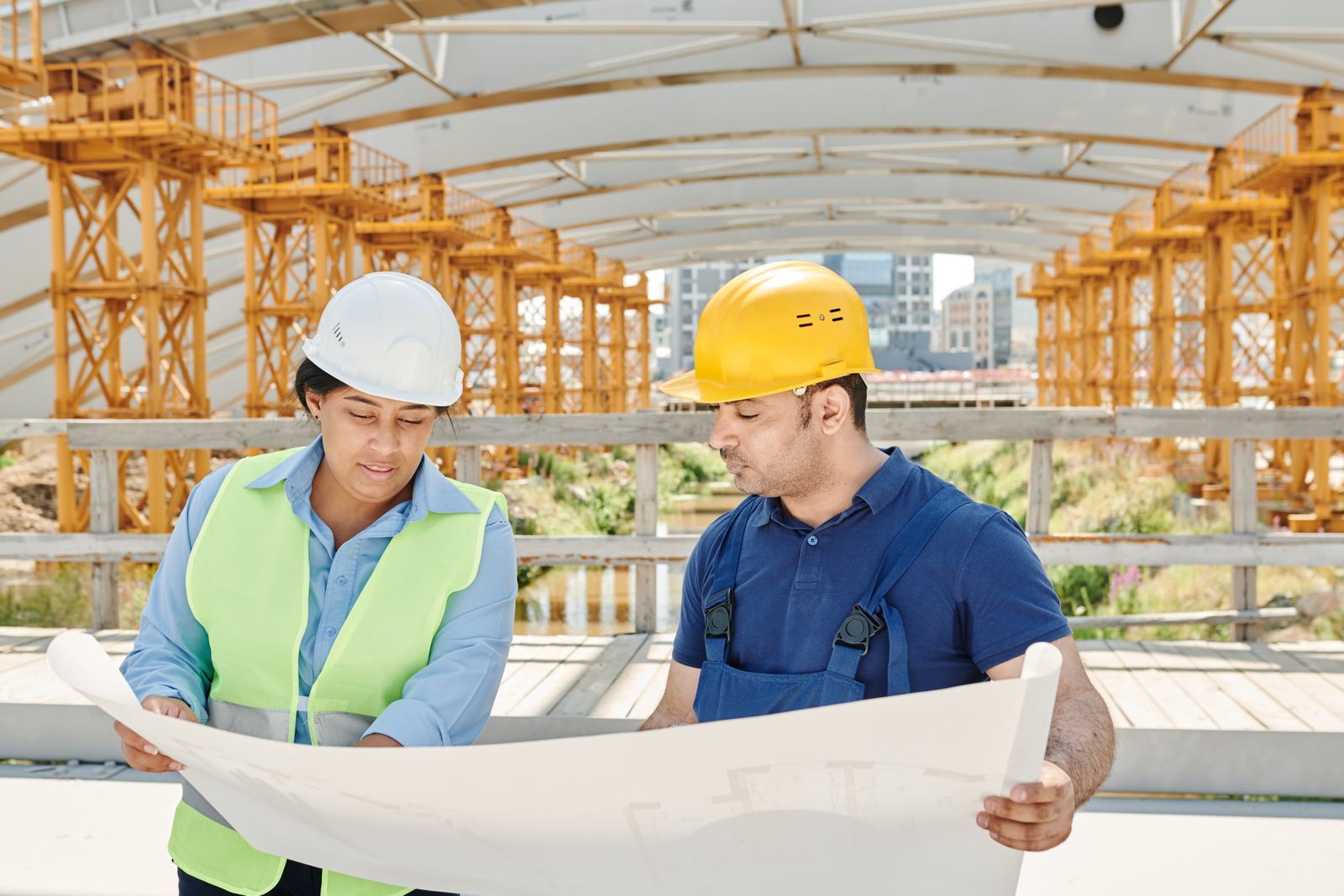 Engineers in safety equipment reviewing plans at a construction site